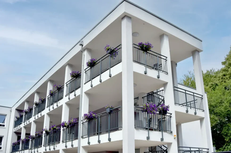 Außenansicht des Senioren- & Pflegeheims Haus Mühlberg in Krettnich mit Balkonen und Blumenkästen vor grüner Umgebung